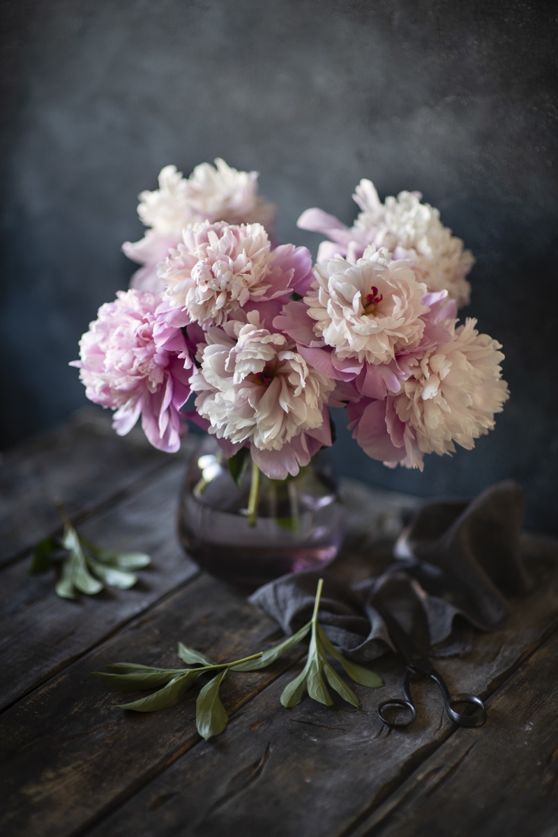 Pink and white peonies in a vase on a wooden table