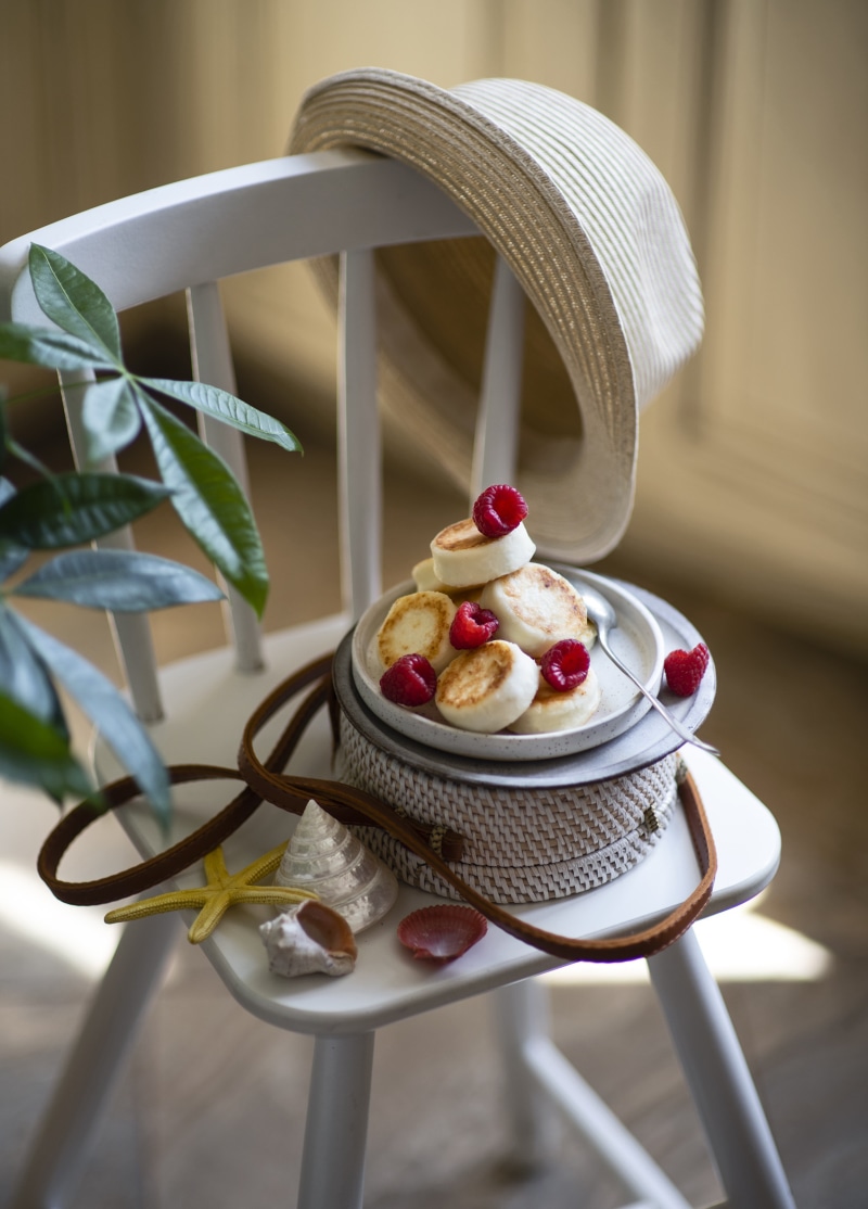 Pancakes with raspberries on a chair with a hat and shells