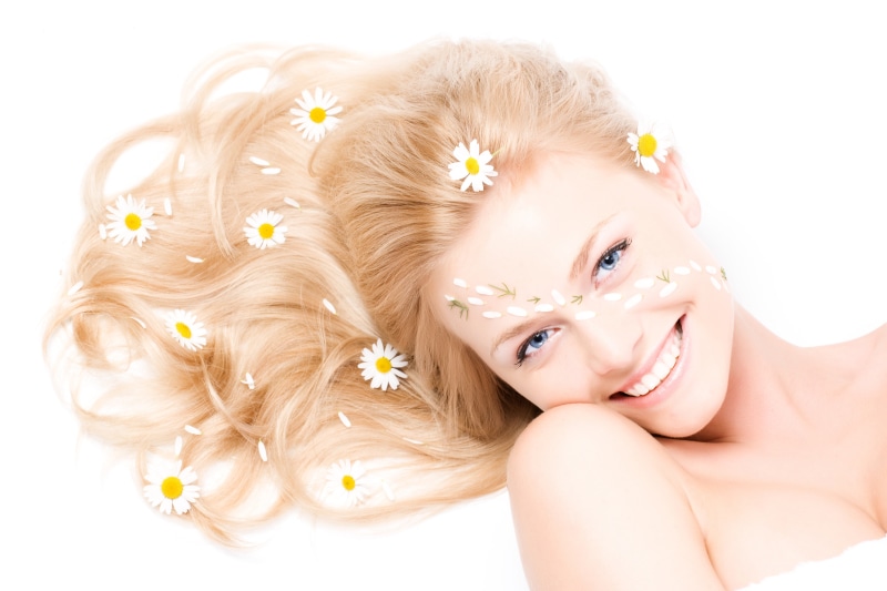 Woman with camomiles in hair and on face