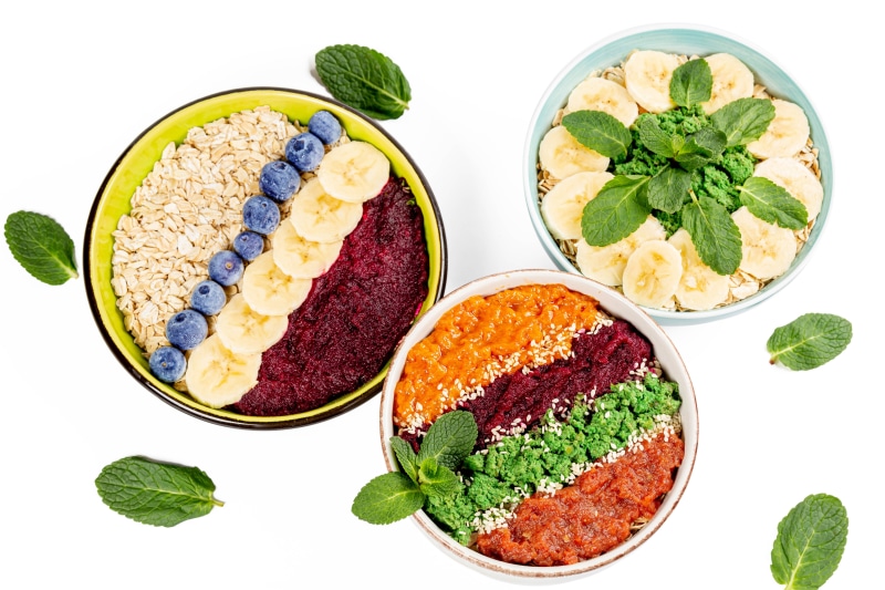 Three bowls of oatmeal with fruit and vegetables