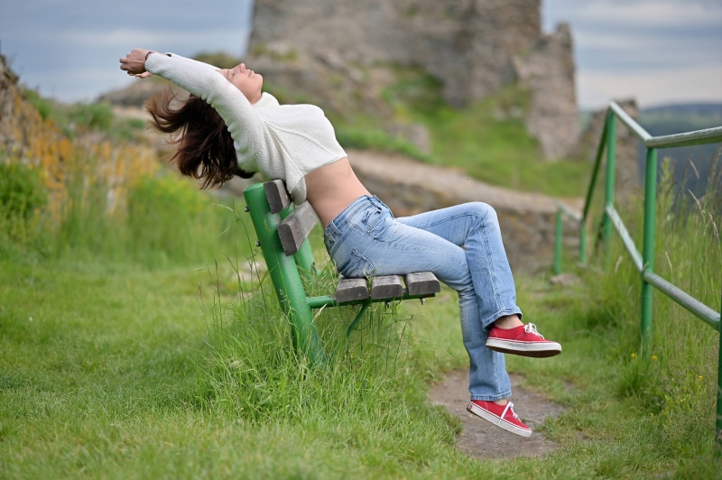 Woman in jeans and sweater sitting on a bench