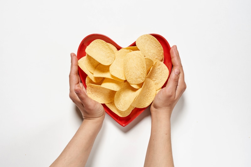 Hands holding a heart-shaped bowl of potato chips