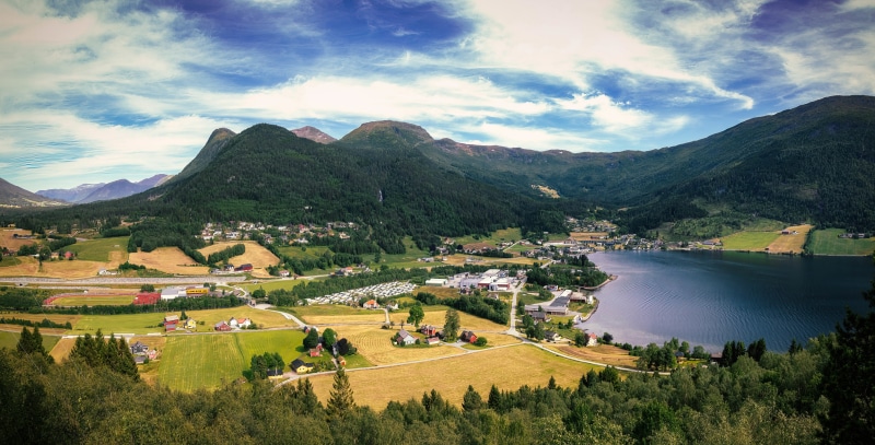 Village and lake in Grodas, Norway with mountains and clouds
