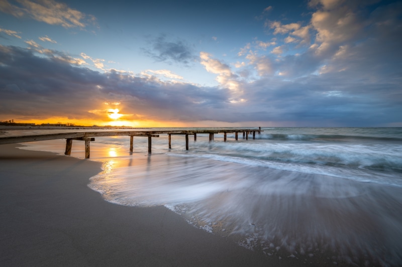 Pier at Heiligenhafen Germany during sunrise with clouds