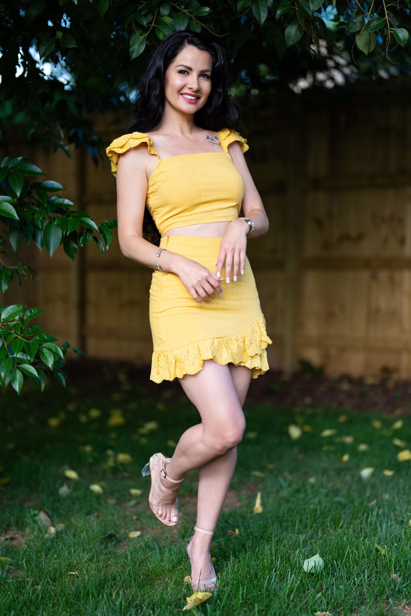 Brunette girl in yellow outfit posing outdoors