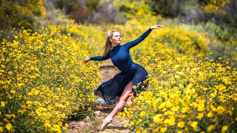 Blonde girl dancing ballet in a field of yellow flowers
