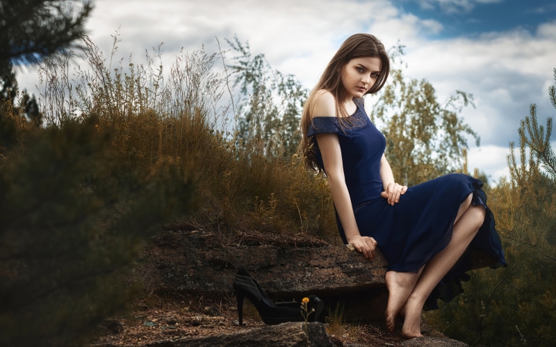 Woman in Blue Dress Sitting on Rock
