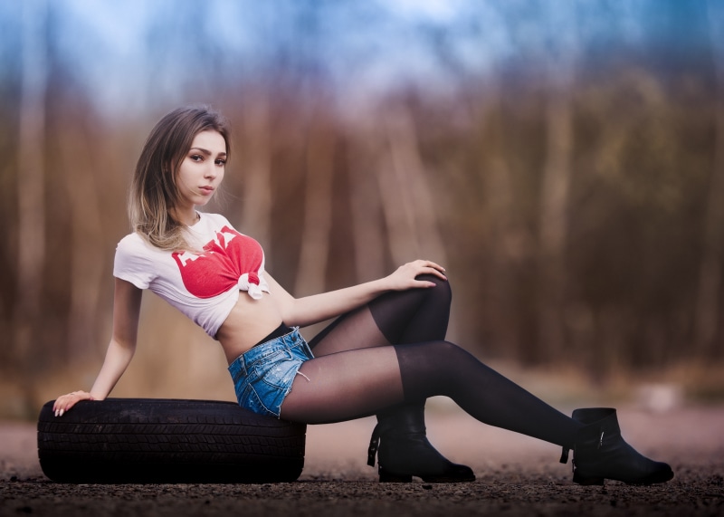 Woman in shorts and pantyhose sitting on tire