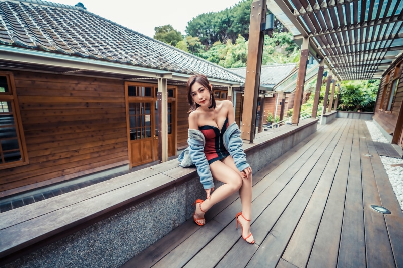 Asian woman in dress sitting on wooden bench