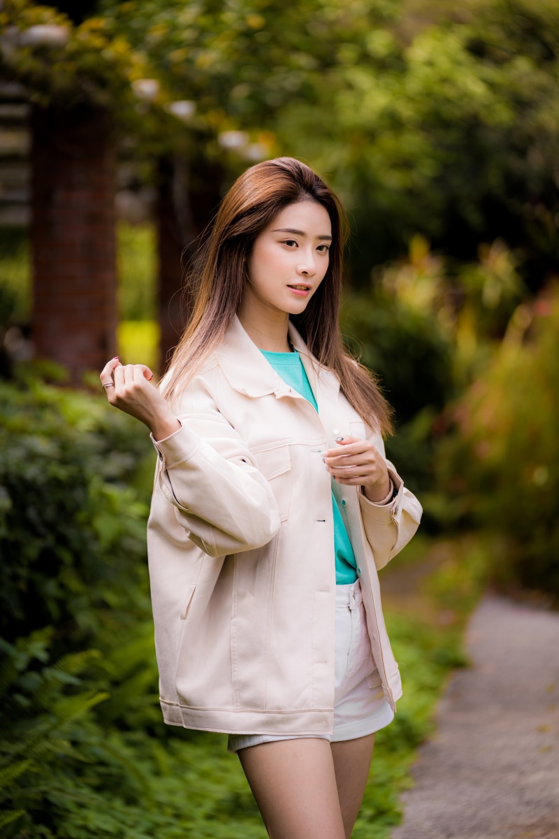 Asian woman in a beige jacket and white shorts posing outdoors