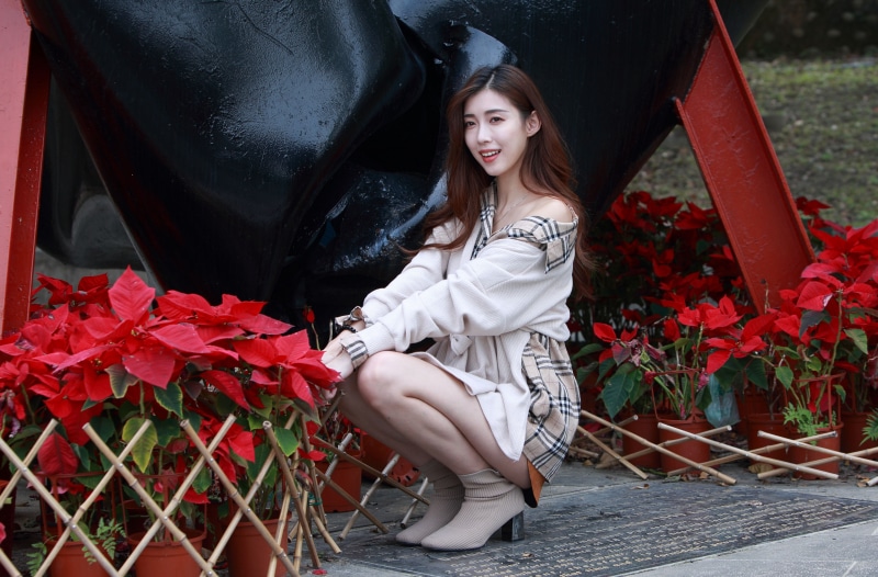 Asian woman posing near red poinsettias