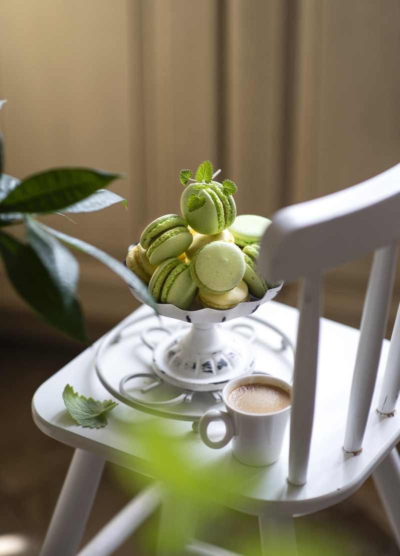 Green macarons and coffee on a white chair