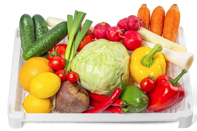 Assortment of fresh vegetables and fruits in a white basket