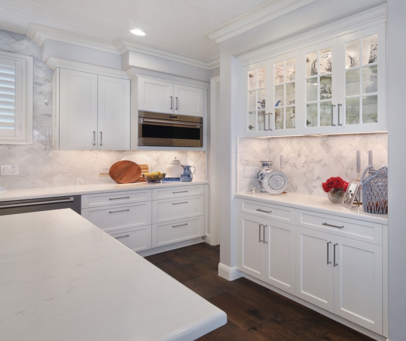 Modern white kitchen with marble backsplash and dark wood floors