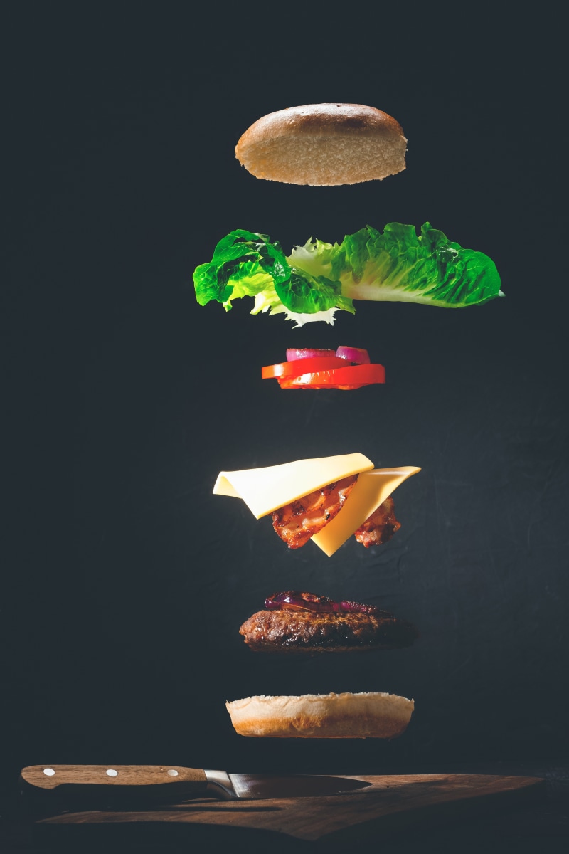 Deconstructed hamburger with knife on dark background