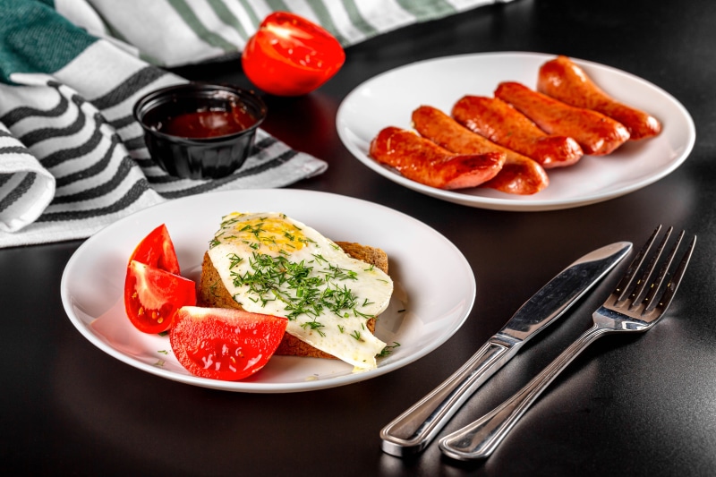 Fried egg on toast with tomatoes and sausages