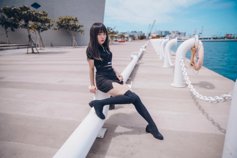 Asian woman sitting on a railing at a waterfront