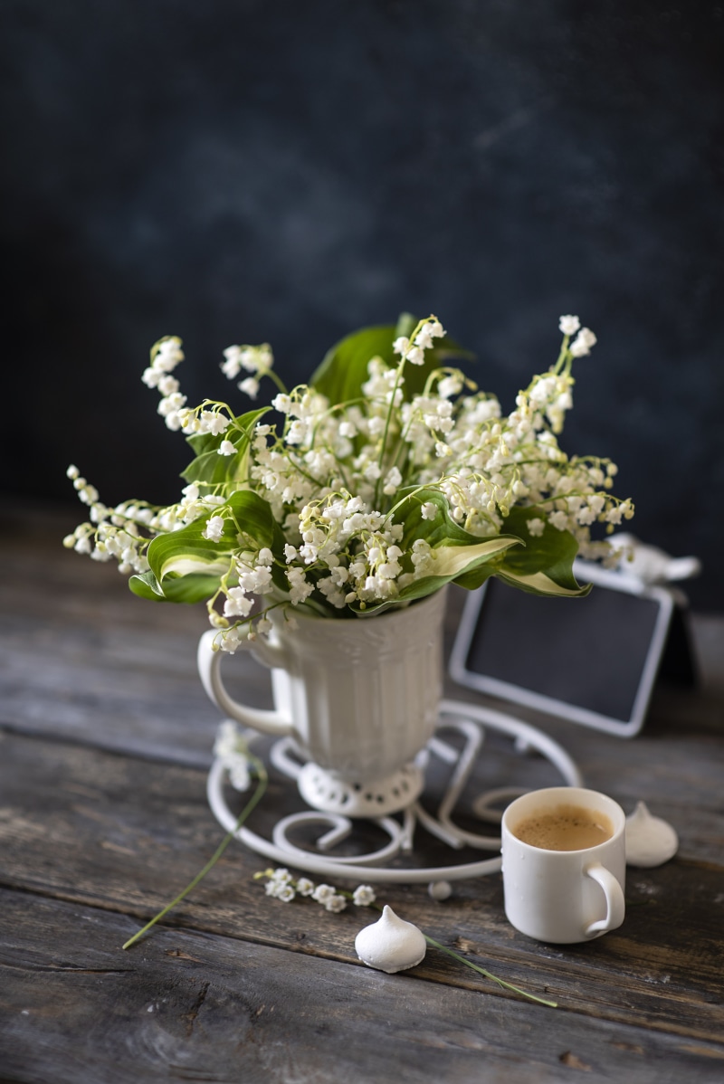 Lily of the valley flowers in a vase with coffee