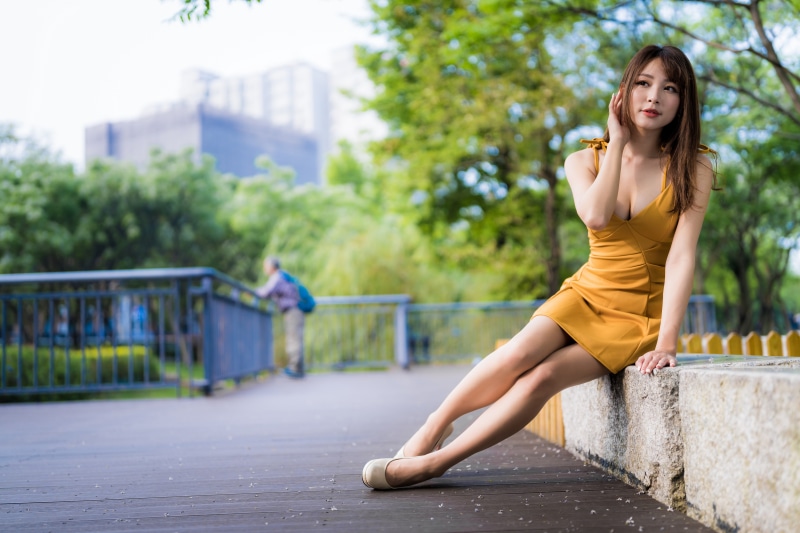 Asian woman in yellow dress sitting in park