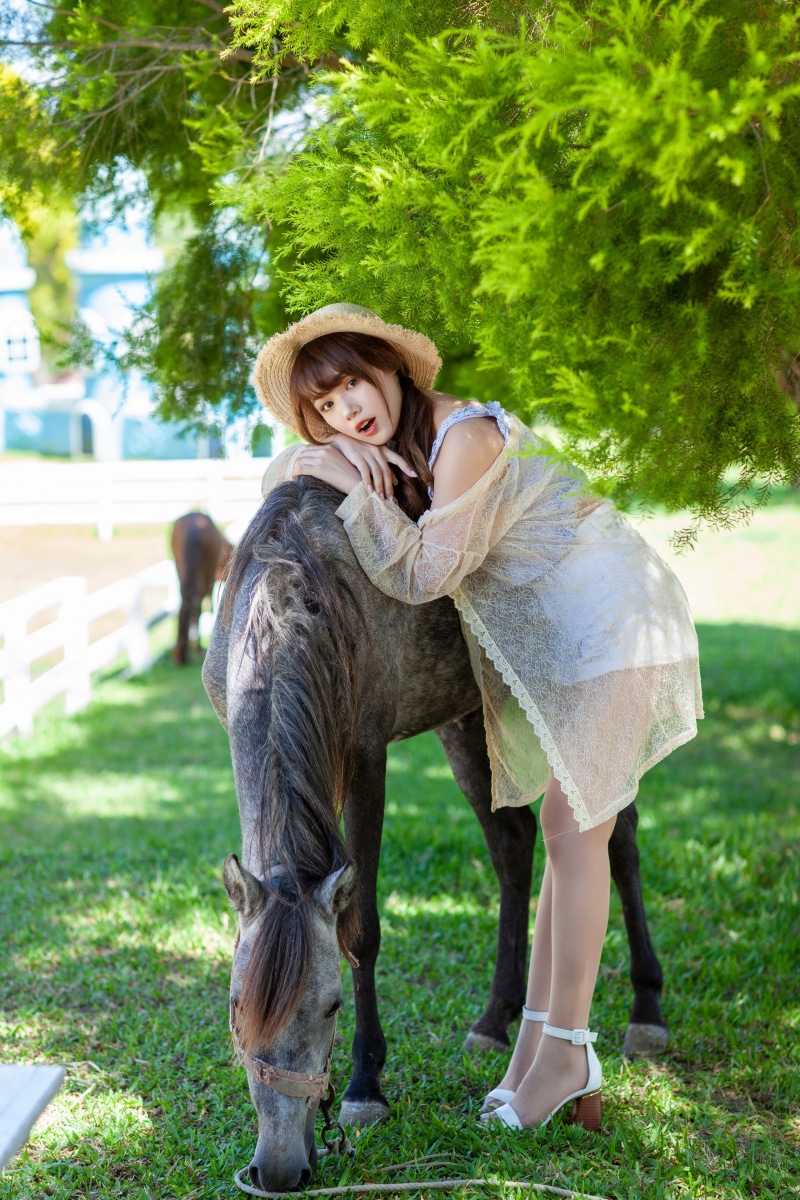Asian woman in straw hat posing with horse