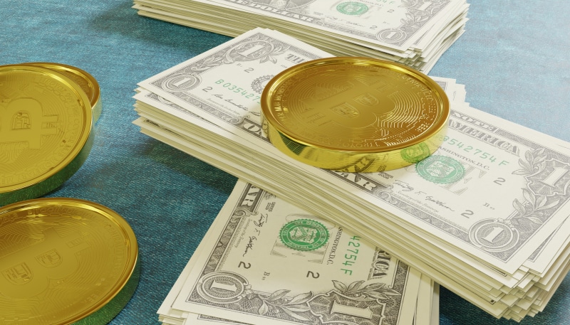Gold Bitcoin coins on stacks of US dollar bills