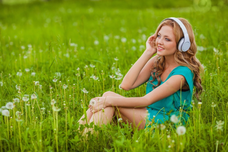 Woman with headphones sitting in grass