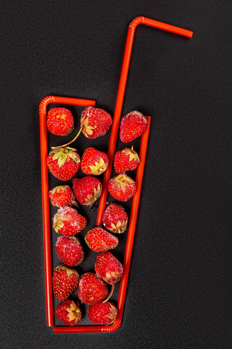 Strawberries arranged in a glass shape with straws