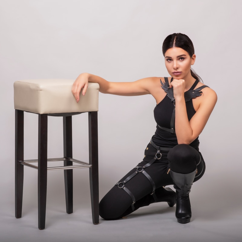 Woman in black outfit posing by a stool