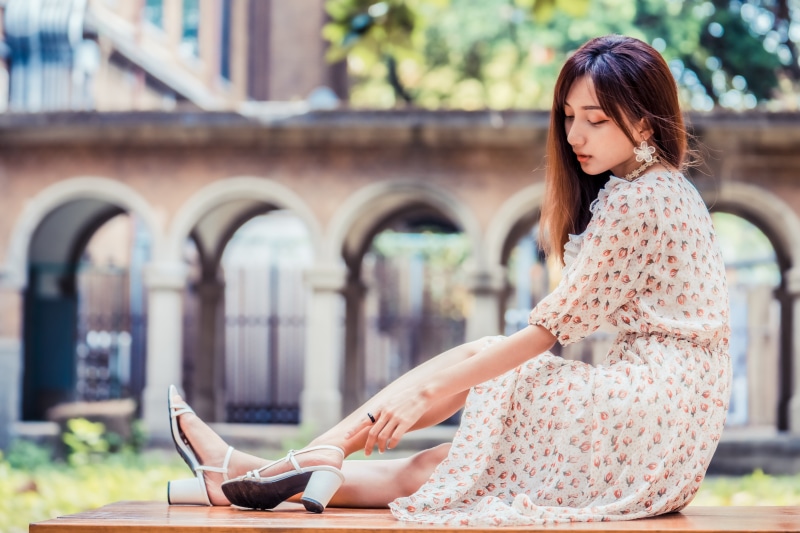 Asian woman in floral dress sitting outdoors