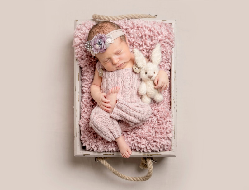 Newborn baby girl sleeping with bunny toy