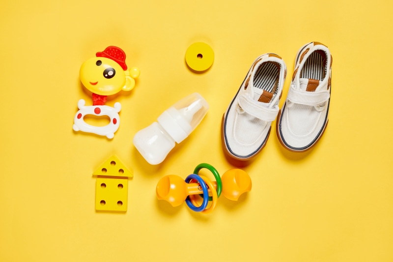 Baby items and shoes on yellow background