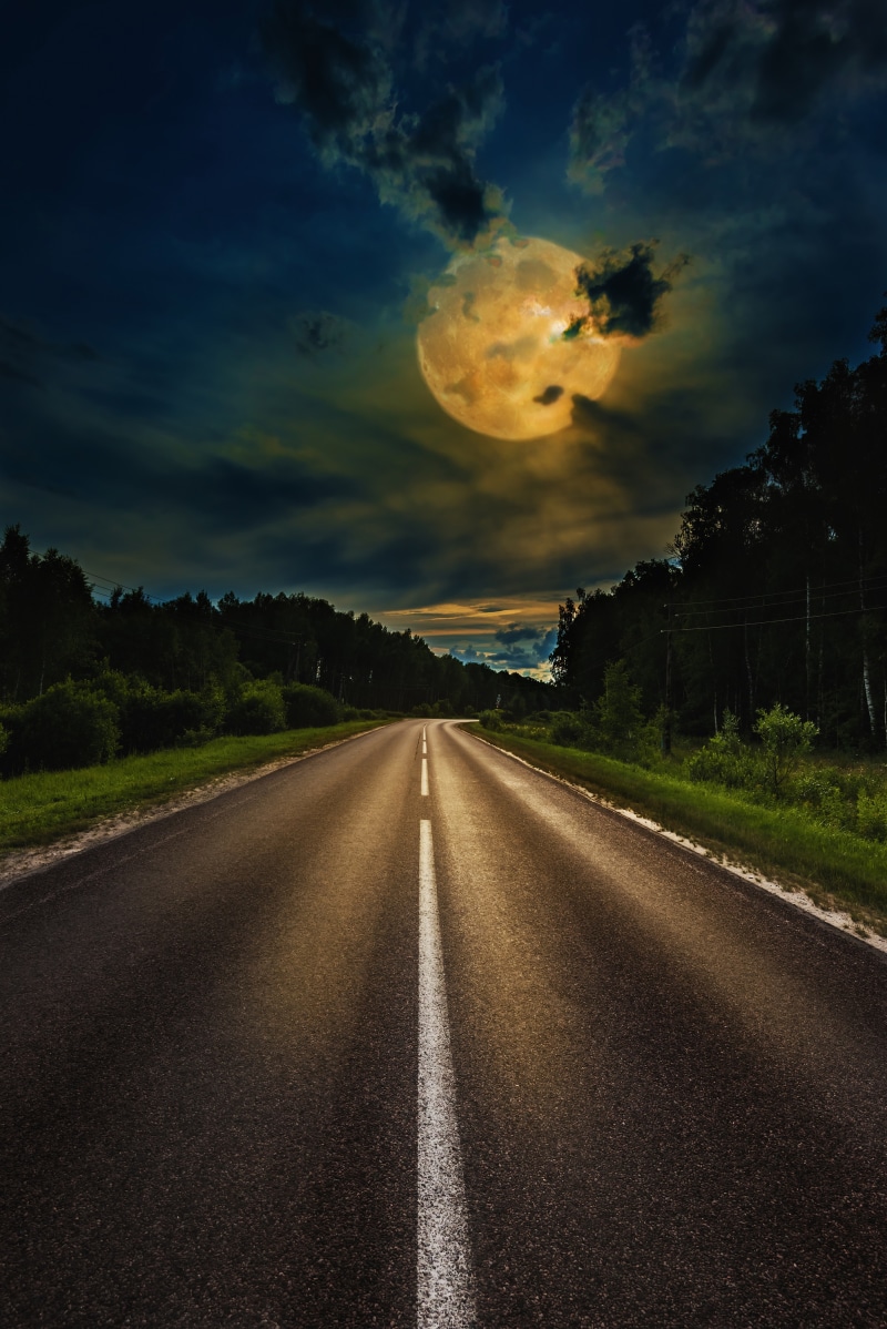 A lonely road under a full moon at night