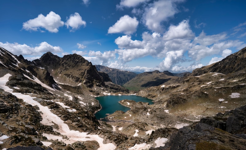 Mountain lake with snow patches and clouds