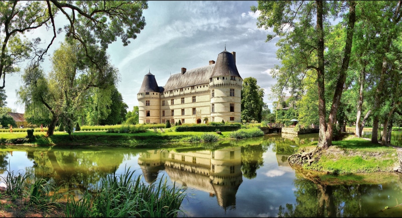 Chateau de l'Islette reflected in a pond surrounded by trees