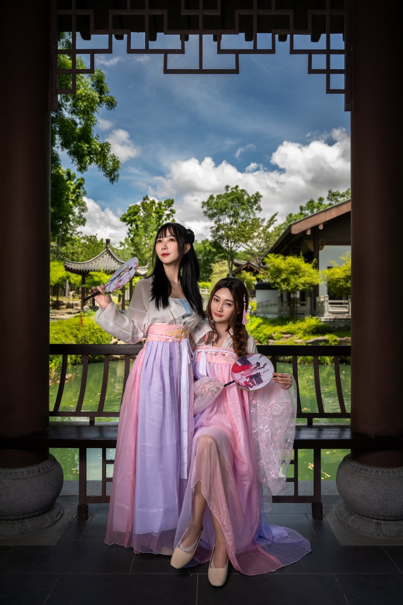Two Asian women in traditional dresses holding fans