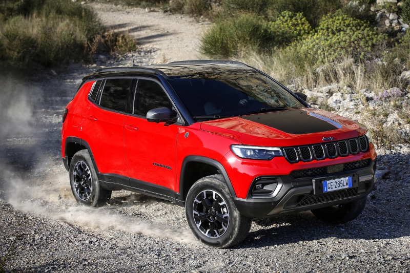 Red Jeep Compass Trailhawk 4xe driving on a dirt road