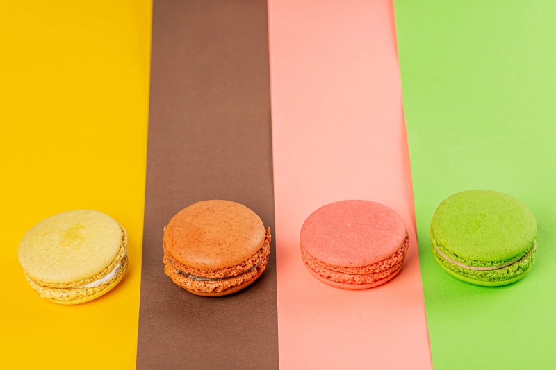Four colorful macarons on a striped background