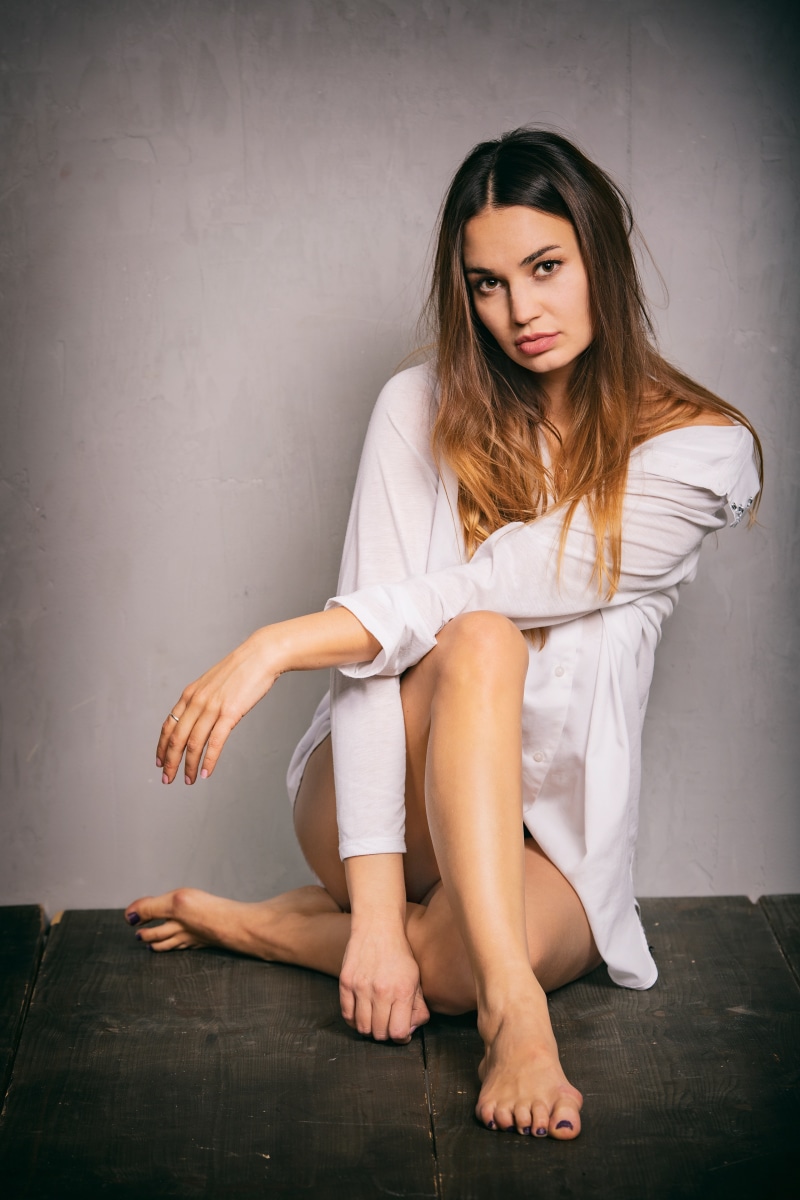 Woman in white shirt sitting on wooden floor