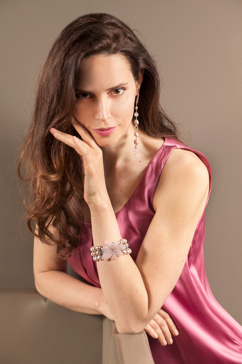 Woman with brown hair wearing a pink dress and jewelry