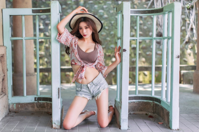 Asian woman in hat and shorts posing