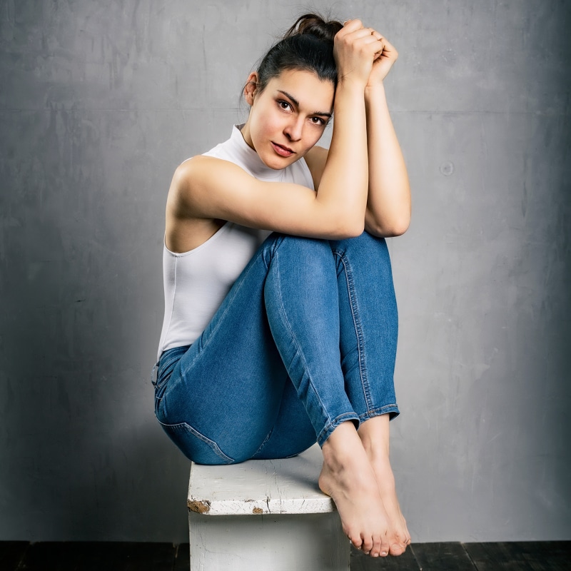 Brunette girl in jeans and singlet sitting