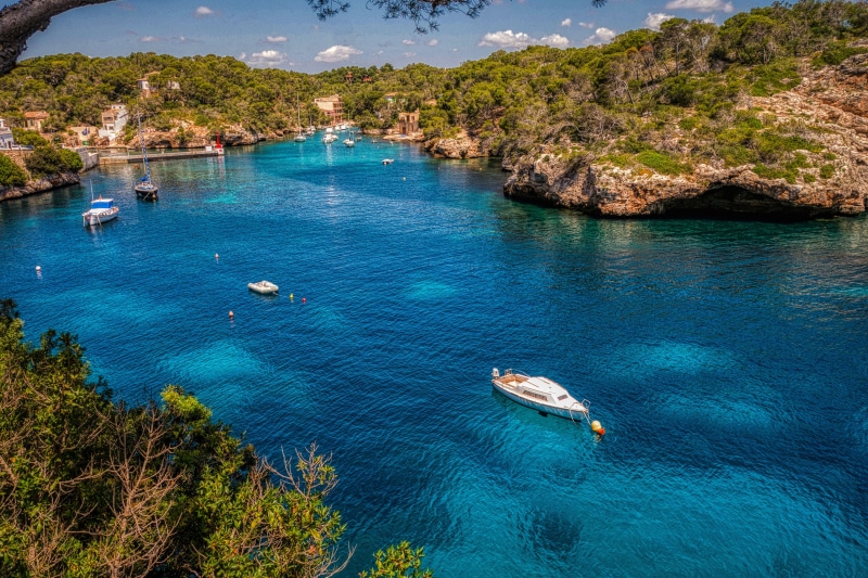 Boats in a clear blue bay with green hills