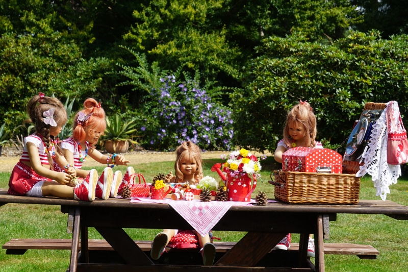 Dolls having a picnic in a garden