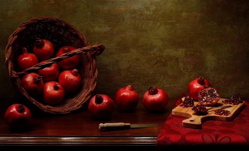 Still-life with pomegranates in a basket and on a cutting board
