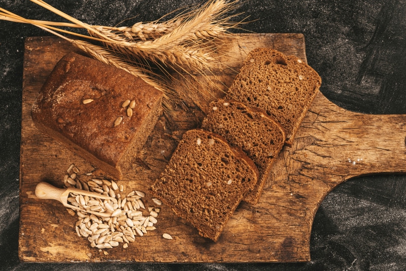 Bread, Sunflower Seeds, and Wheat on a Cutting Board