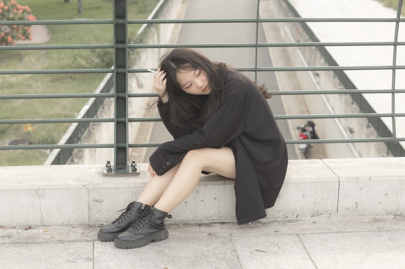 Brunette girl in suit jacket and boots sitting