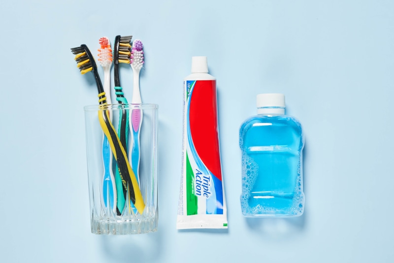 Toothbrushes, toothpaste, and mouthwash on blue background