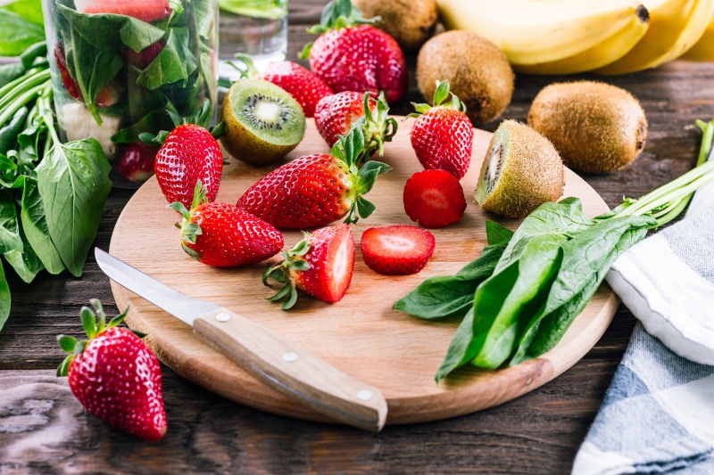 Strawberries, Kiwis, Bananas, Spinach, and Knife on Cutting Board