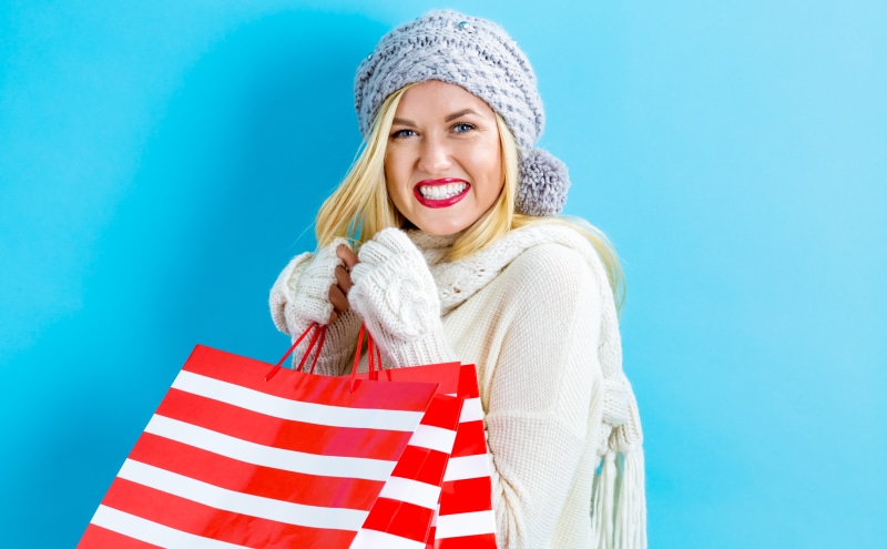 Blonde girl in winter hat with shopping bags