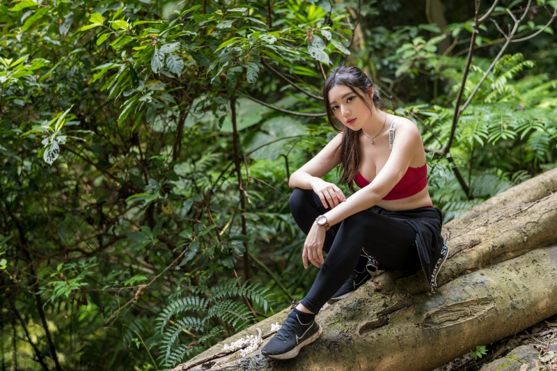 Asian woman sitting on a log in a forest